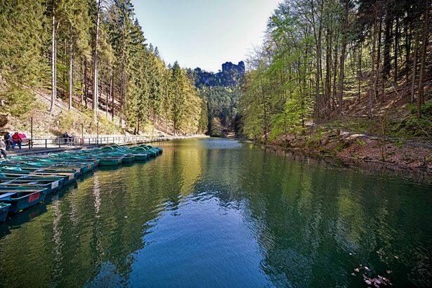 Boote auf dem Amselsee mit Wald im Hintergrund. Klarer blauer Himmel.